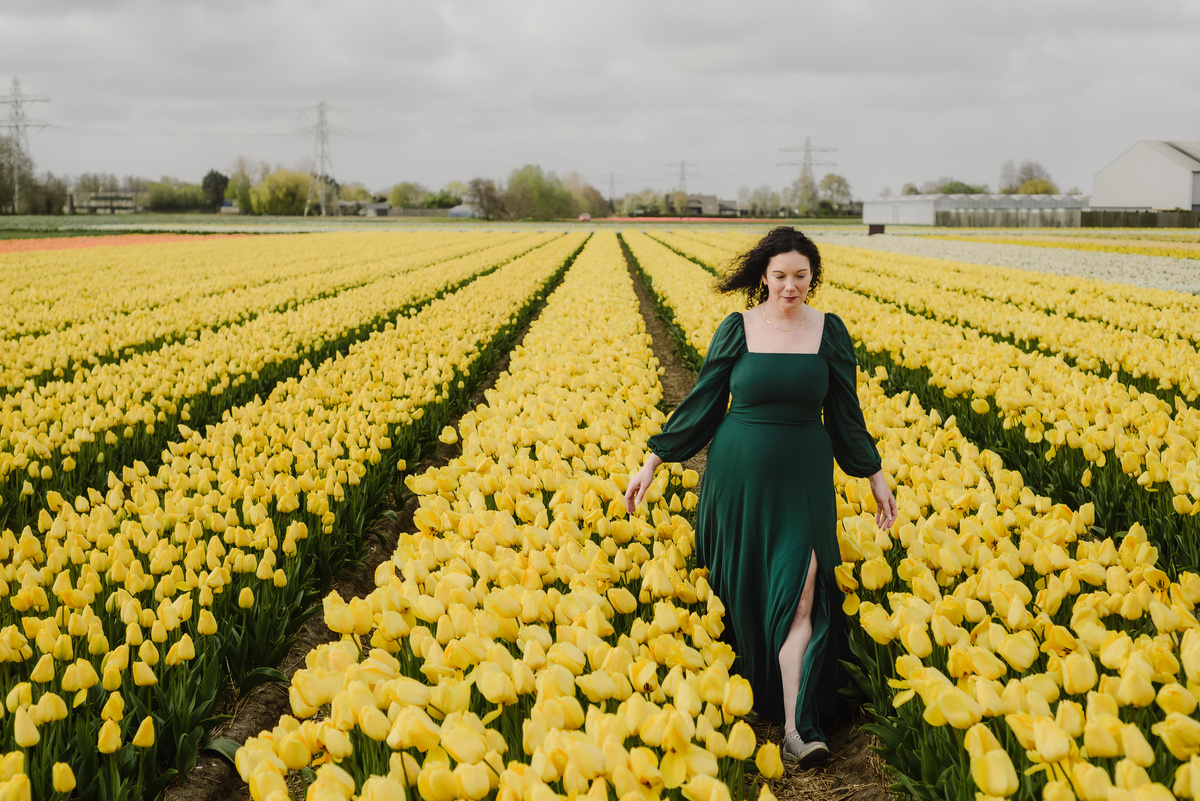 Woman walking through yellow tulip fields in the Netherlands.