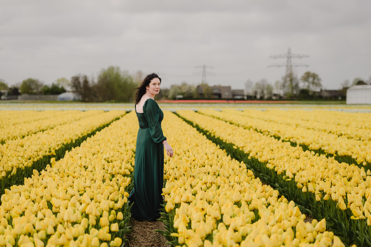 Woman walking through yellow tulip fields in the Netherlands.