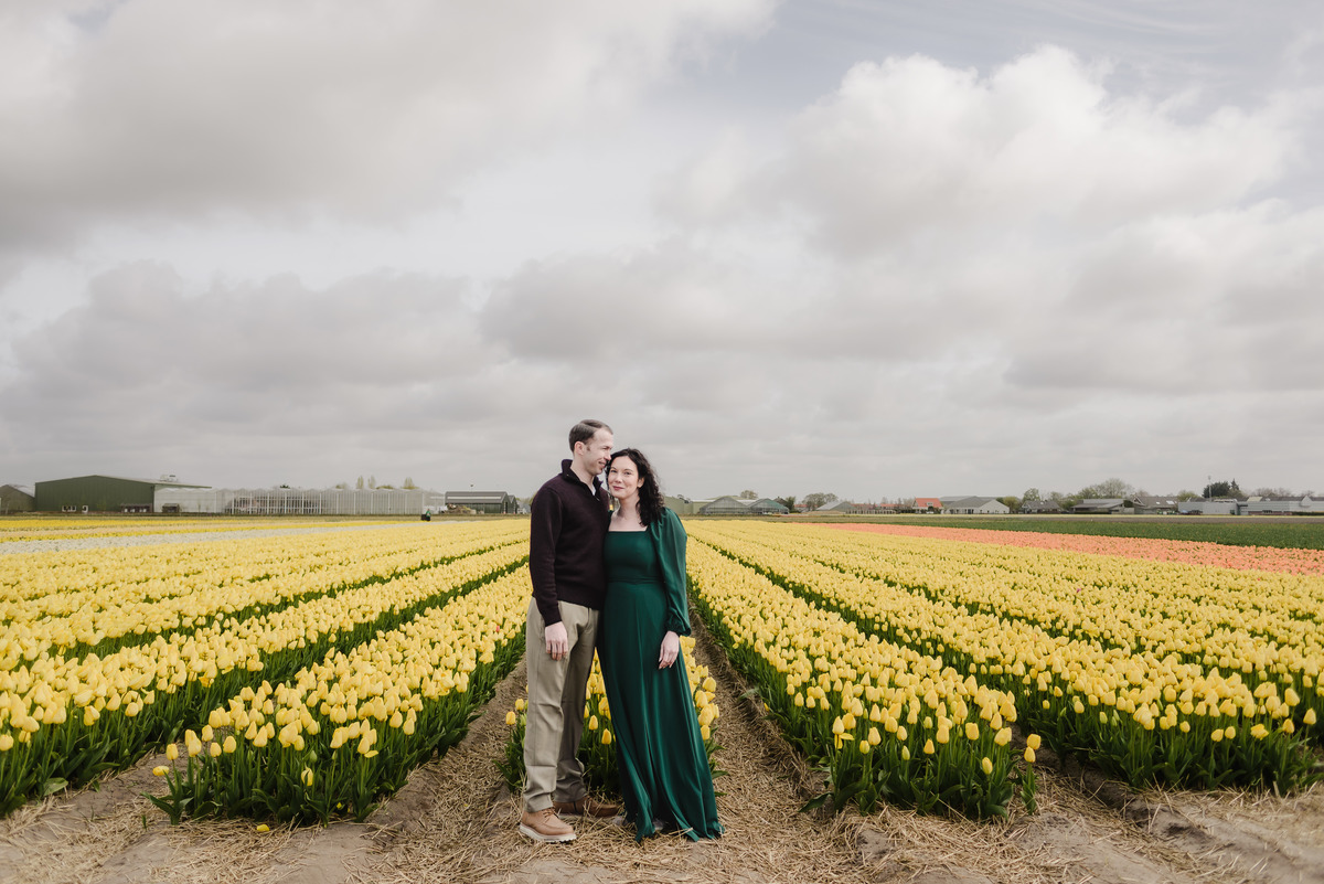 Portrait of a couple surrounded by blooming yellow tulips.