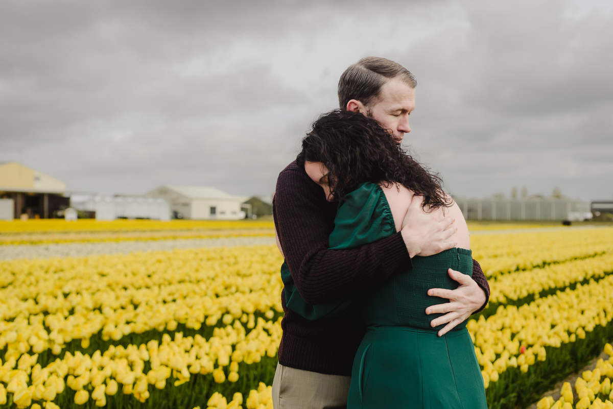 Couple embracing in a private tulip field during spring.