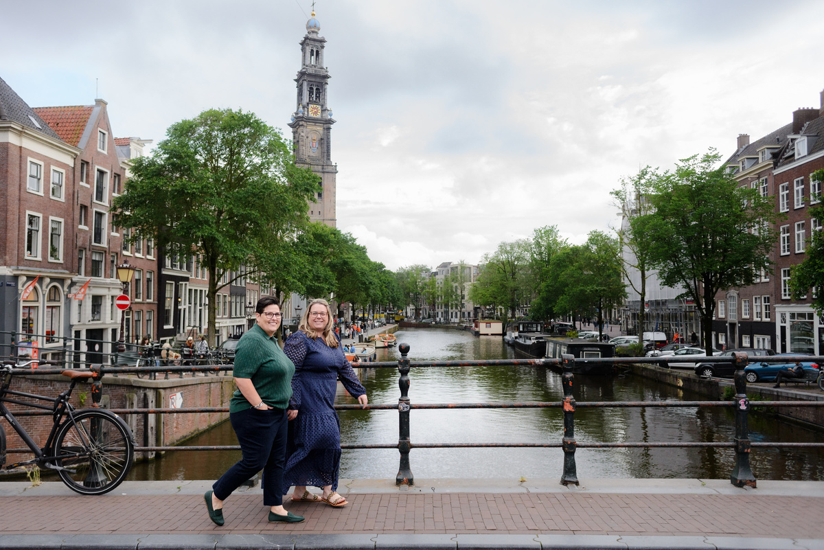Couple walking hand in hand along a canal during an Amsterdam photo session.