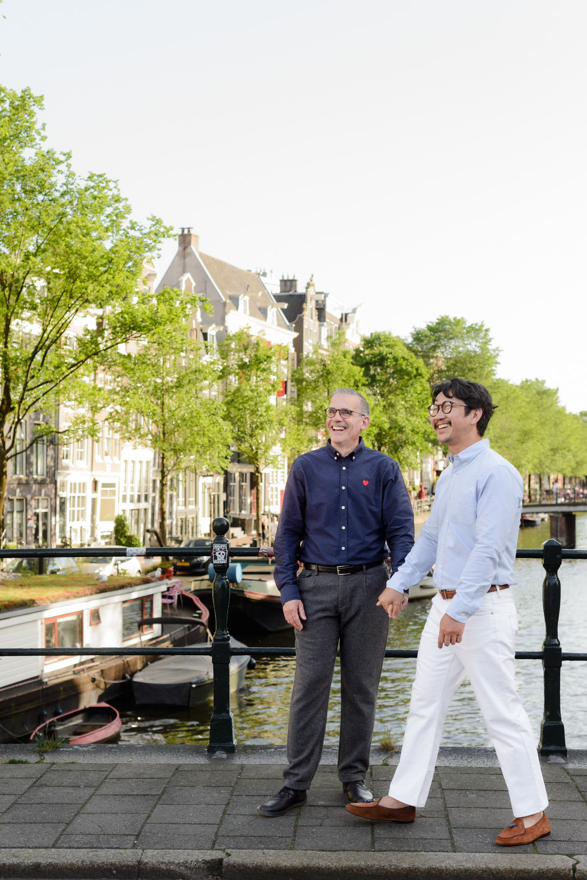 Couple holding hands beside a canal in Amsterdam.