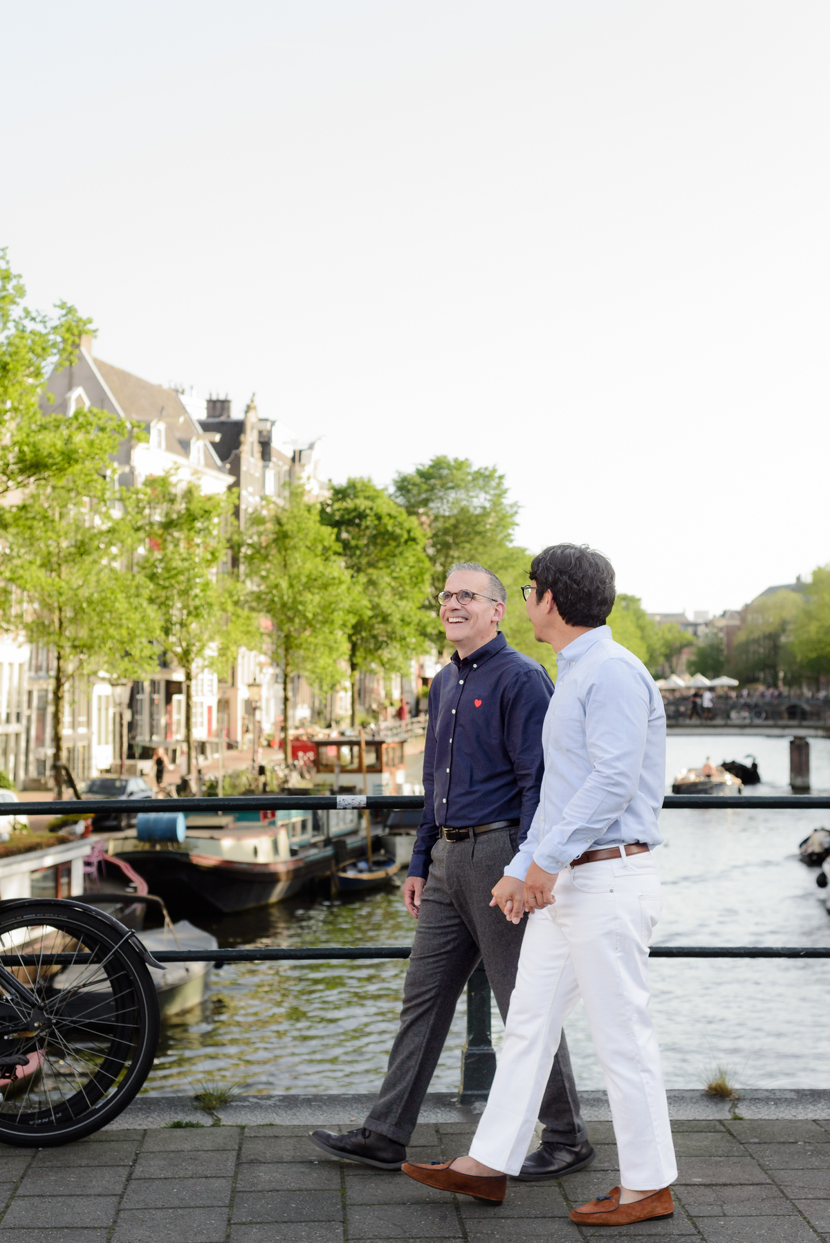 Couple holding hands beside a canal in Amsterdam.