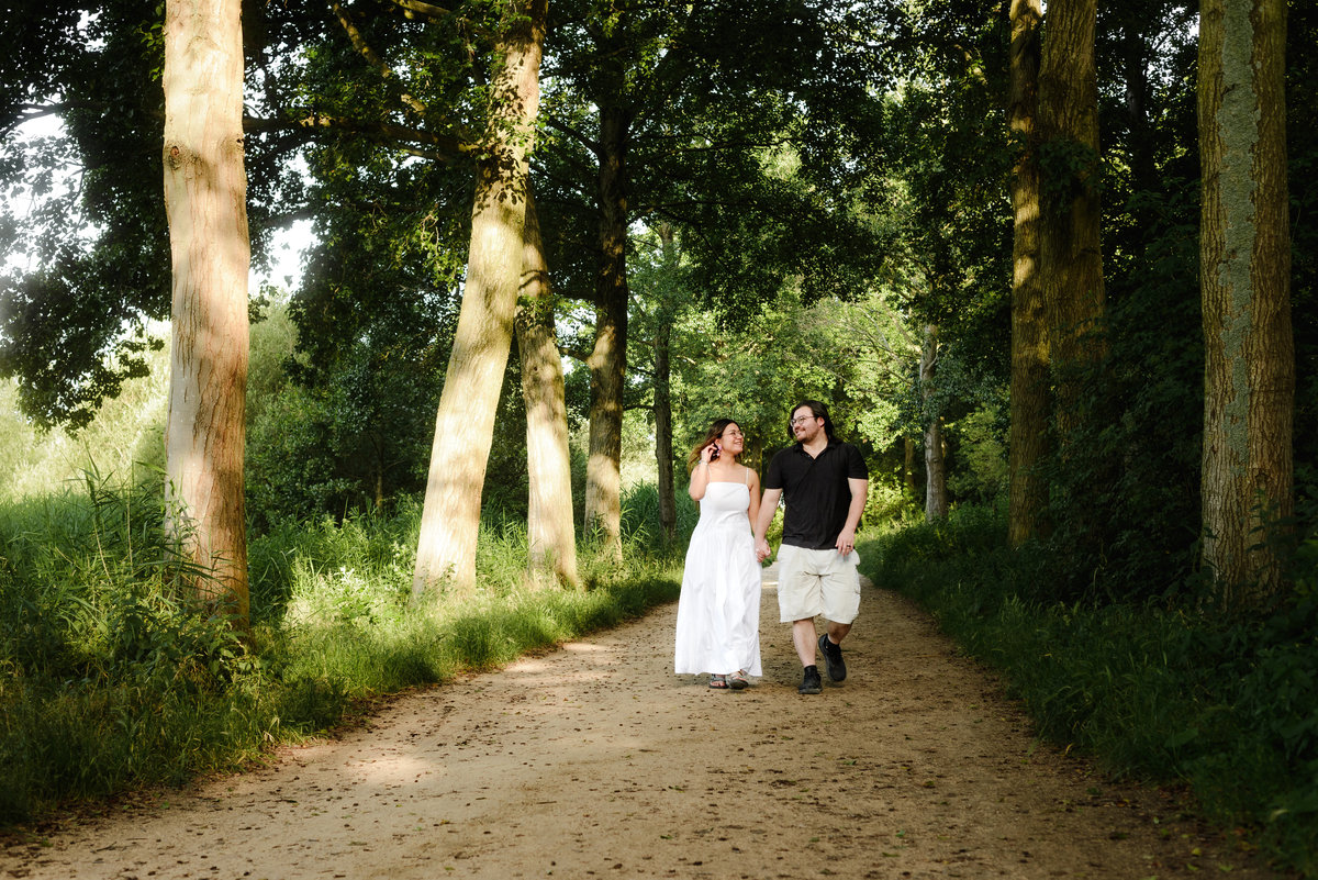 Couple holding hands beneath trees during an Amsterdam engagement session.