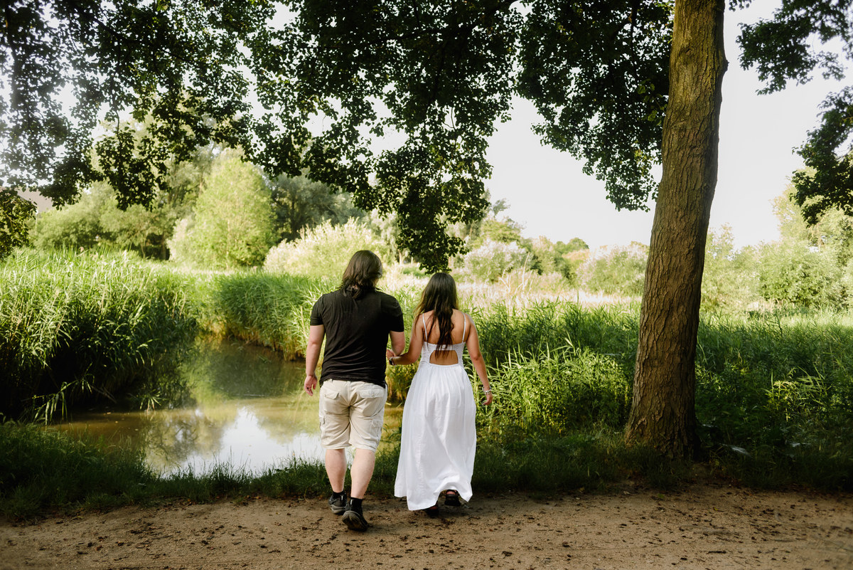 ngaged couple walking through Westerpark during a natural photo session.