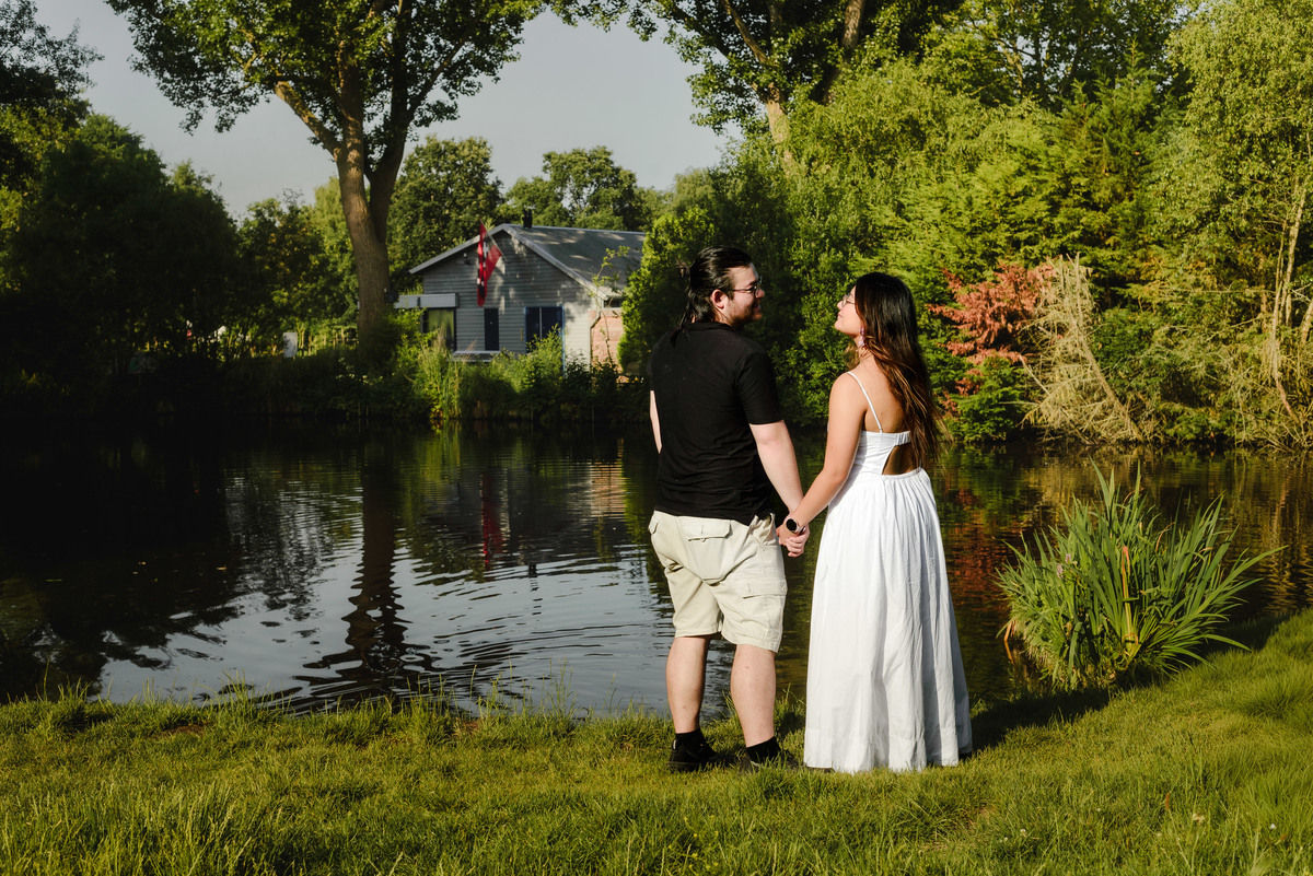 Engaged couple smiling beside a pond in Westerpark.