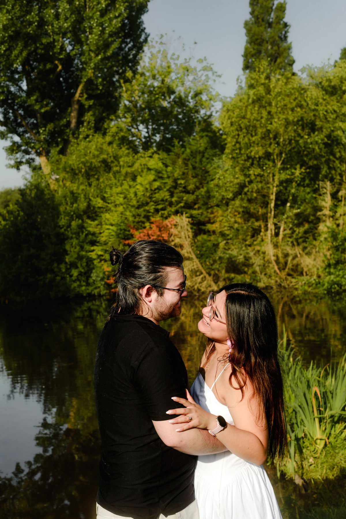 Engaged couple smiling beside a pond in Westerpark.