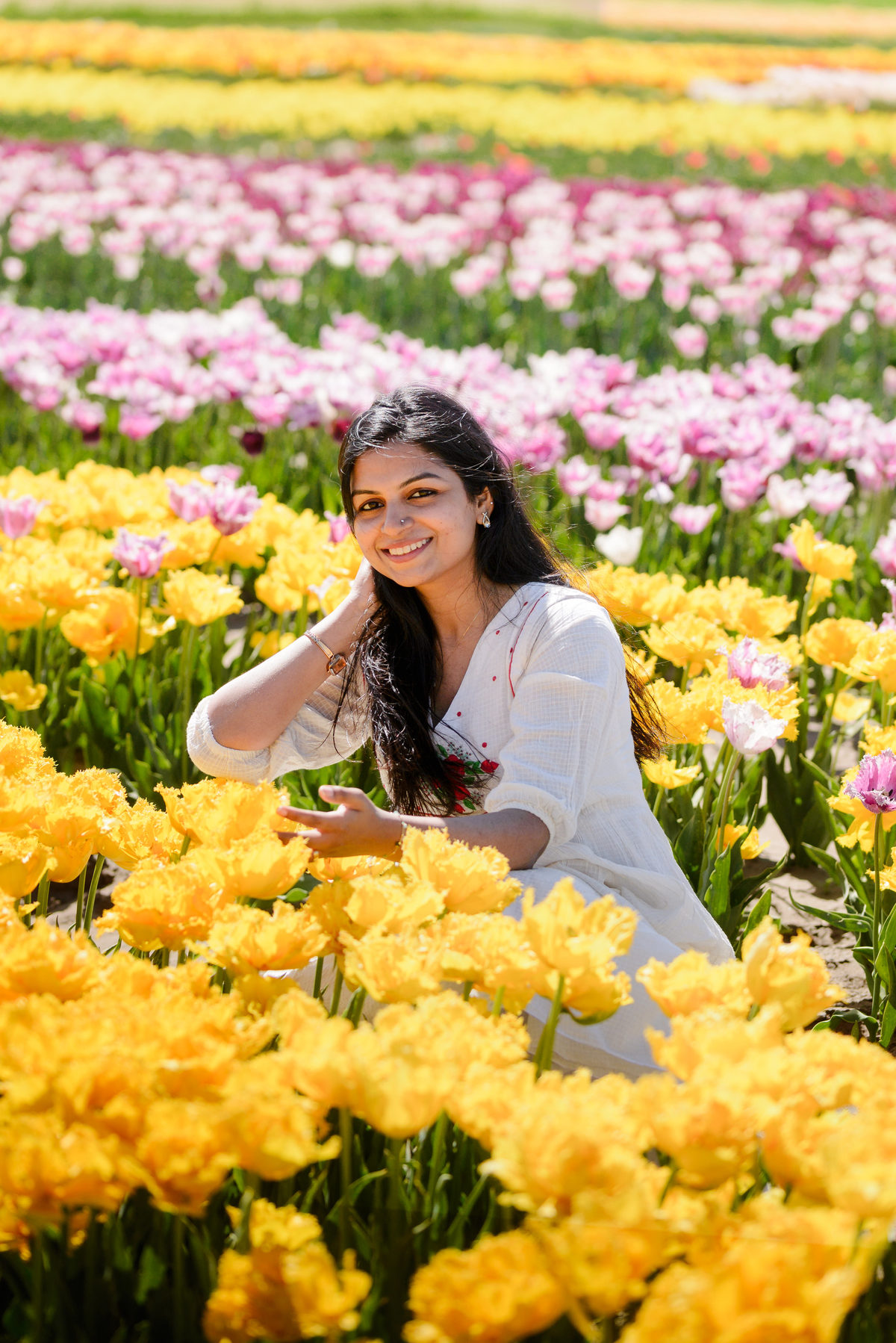 Woman smiling among colourful tulips at The Tulip Barn in the Netherlands.