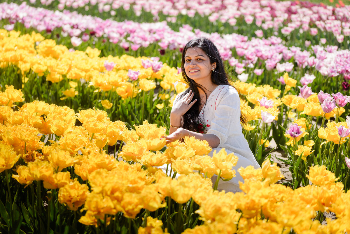 Portrait of a woman surrounded by vibrant spring flowers during tulip season.