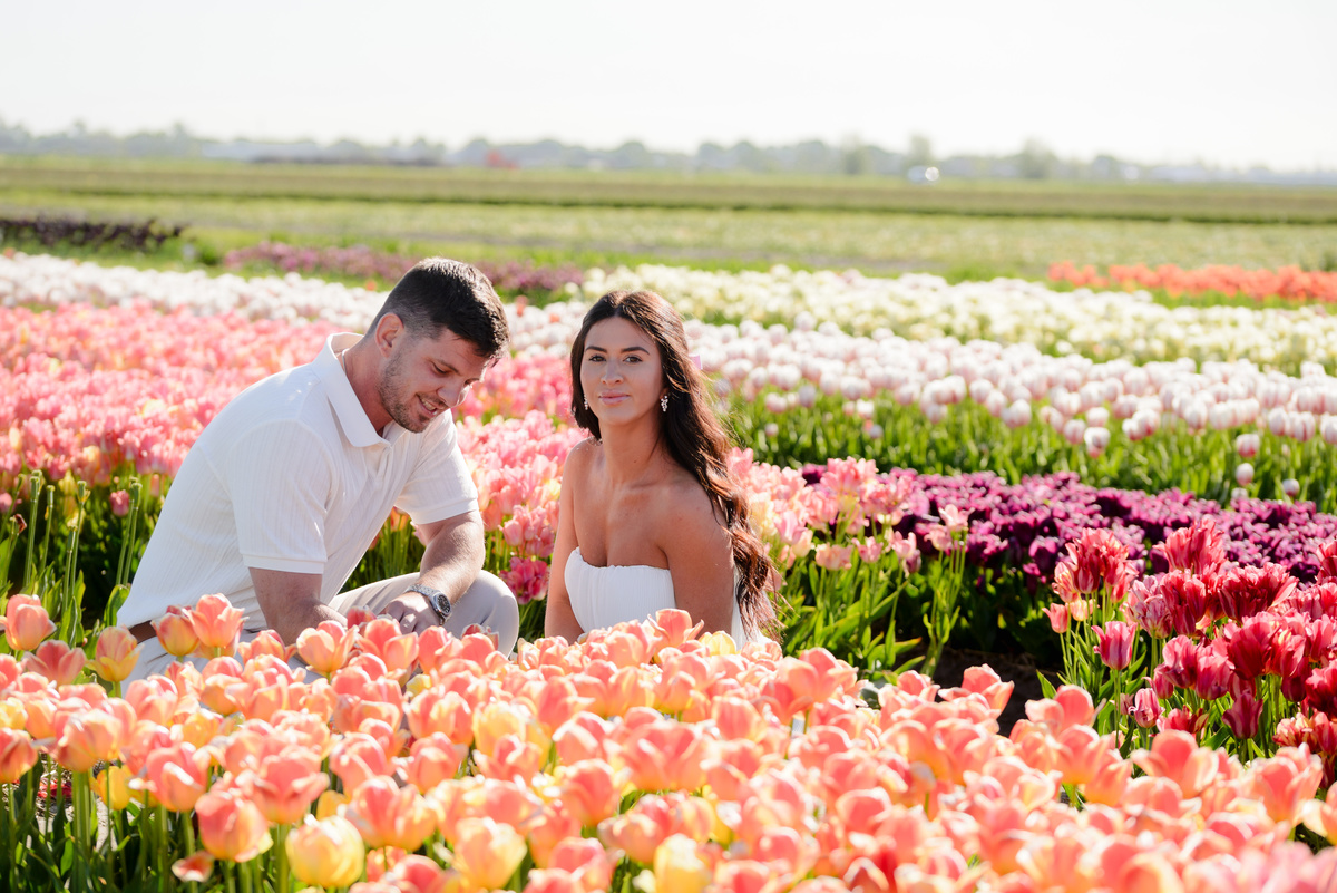 Newly engaged couple celebrating among blooming tulips.