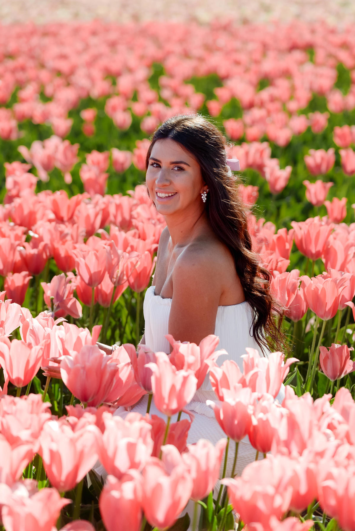 Portrait of a woman surrounded by pink flowers during tulip season in the Netherlands.