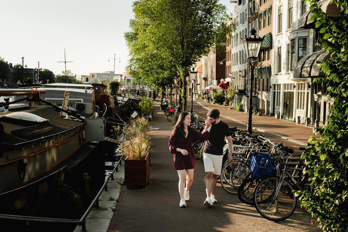 Couple walking through Amsterdam after their canal boat proposal.