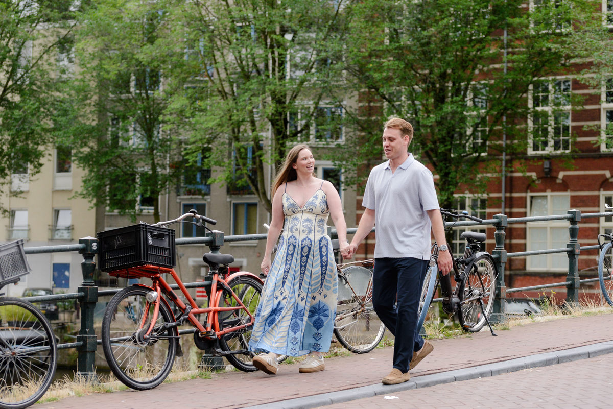 Newly engaged couple walking beside Oudeschans in Amsterdam