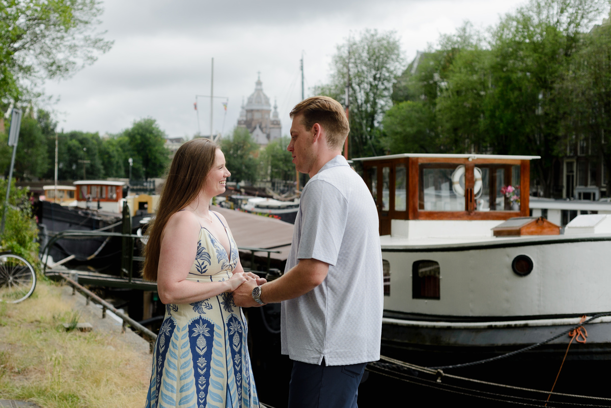 Newly engaged couple photographed near boats in central Amsterdam