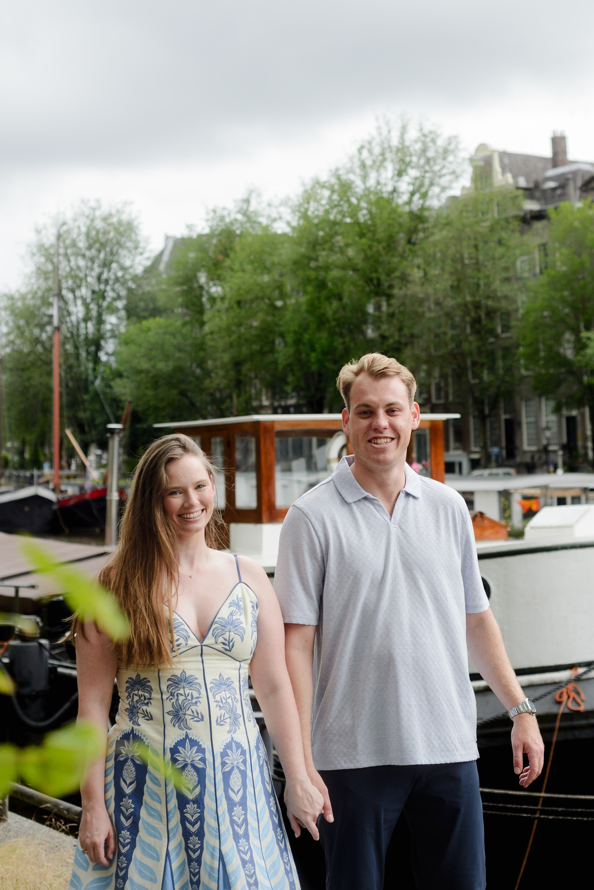 Newly engaged couple photographed near boats in central Amsterdam
