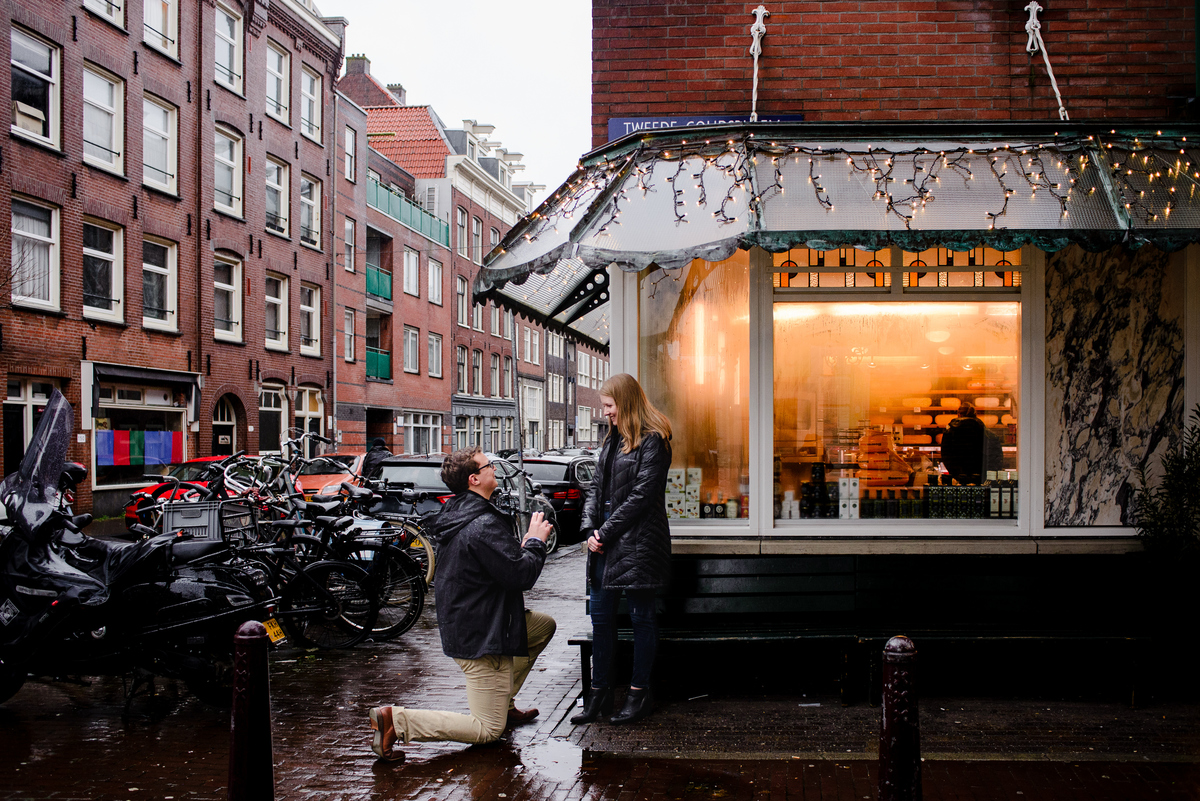 Surprise marriage proposal on an Amsterdam street with bicycles and historic architecture around the couple.