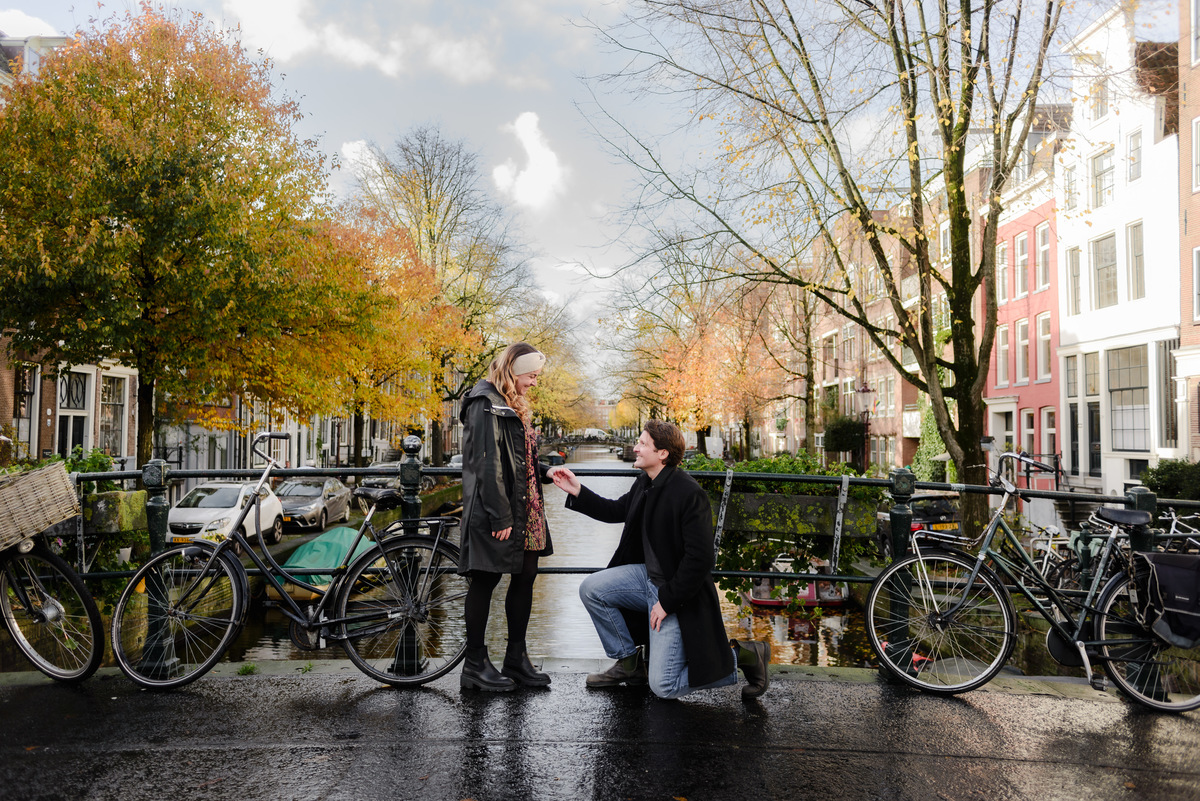 Autumn surprise proposal in Amsterdam surrounded by bicycles, canal houses and golden trees.