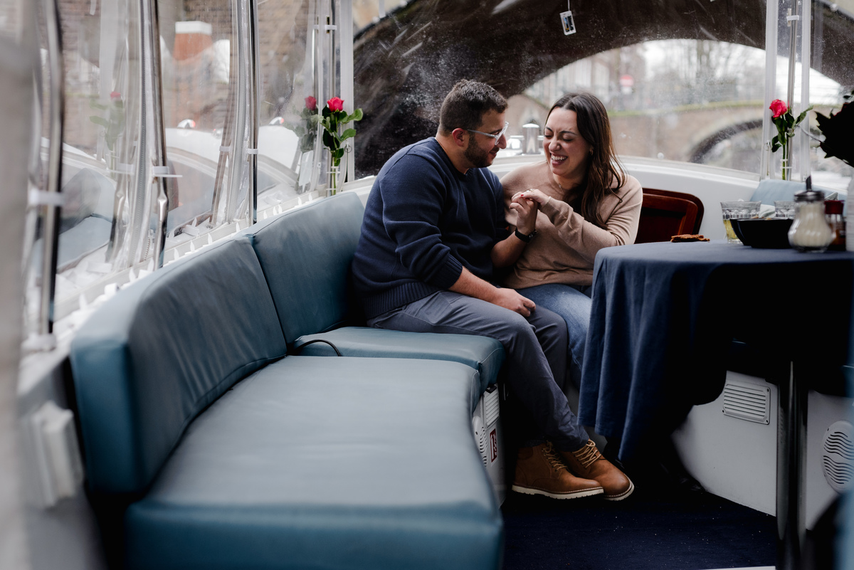 Newly engaged couple celebrating together on a private canal boat in Amsterdam.