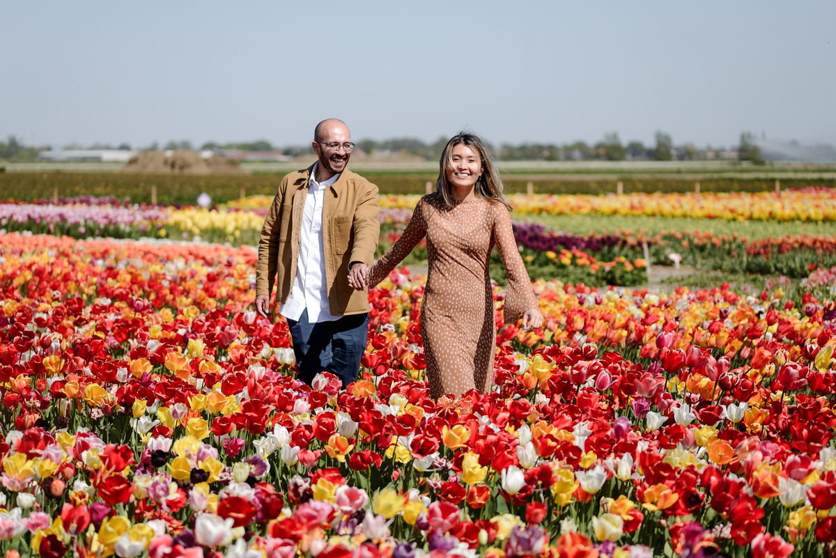Playful couple walking through the colourful tulip garden