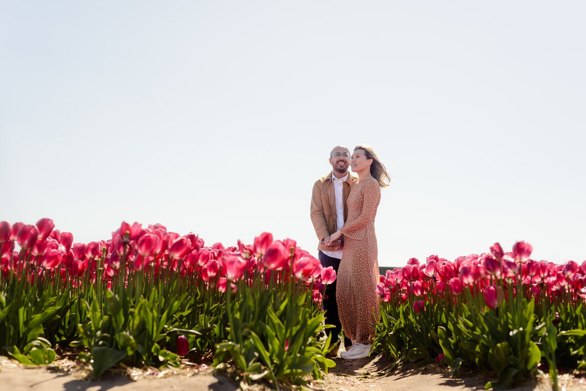 Happy newly engaged couple embracing in a Dutch tulip garden
