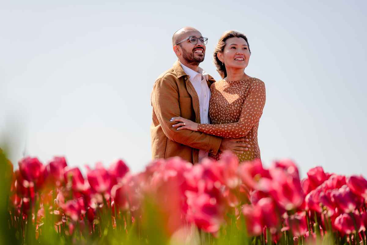 Happy newly engaged couple embracing in a Dutch tulip garden