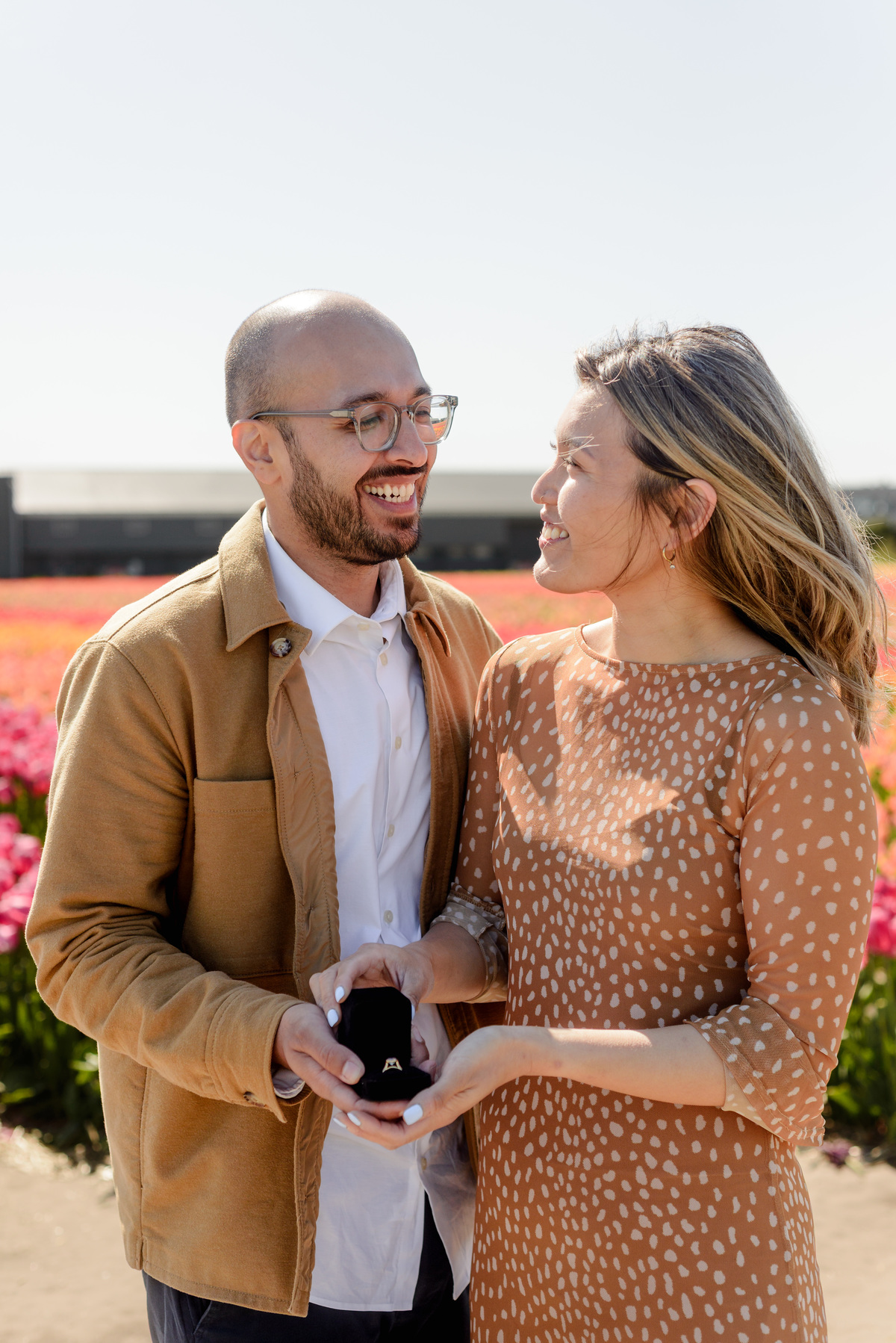 Happy newly engaged couple embracing in a Dutch tulip garden