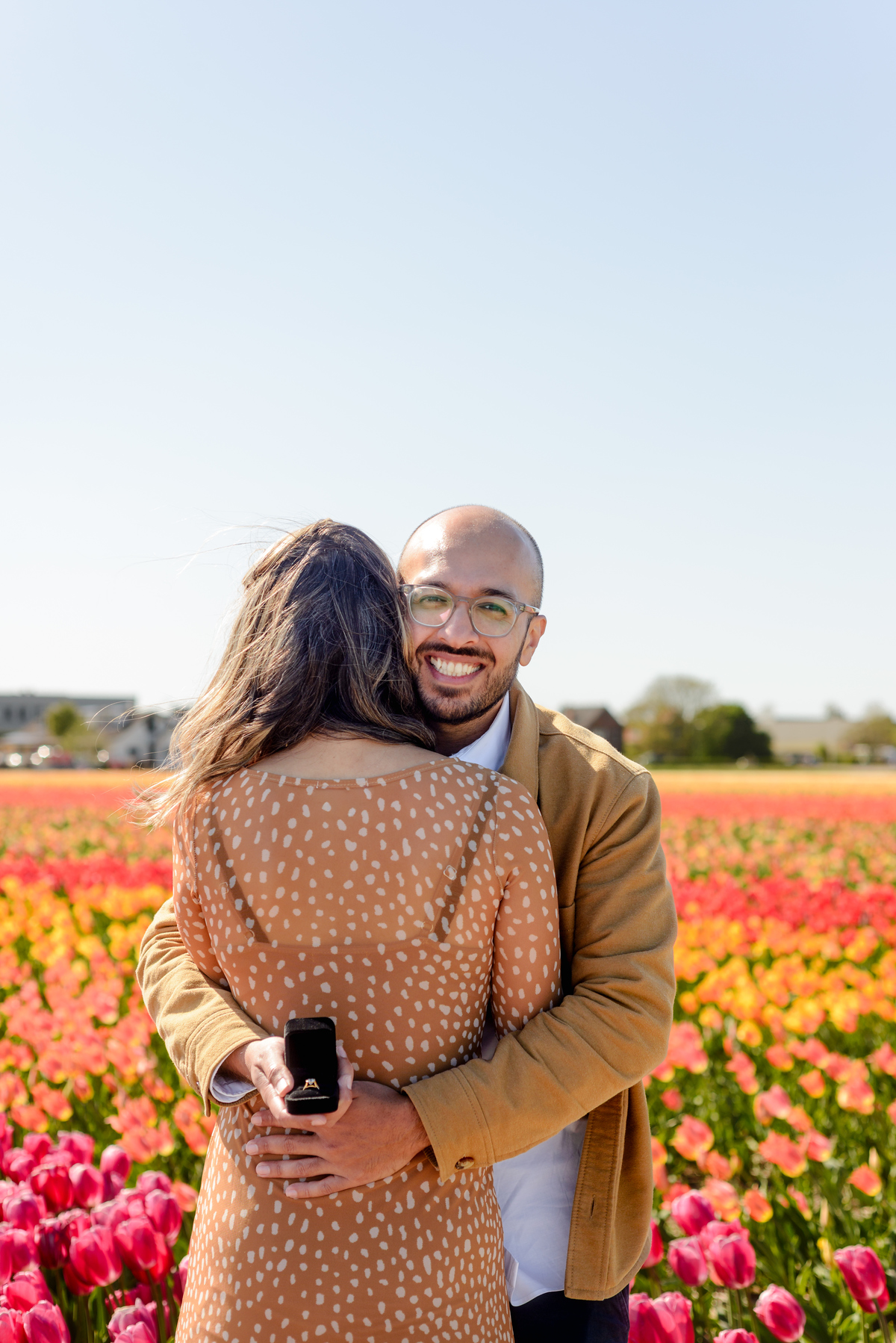 Happy newly engaged couple embracing in a Dutch tulip garden