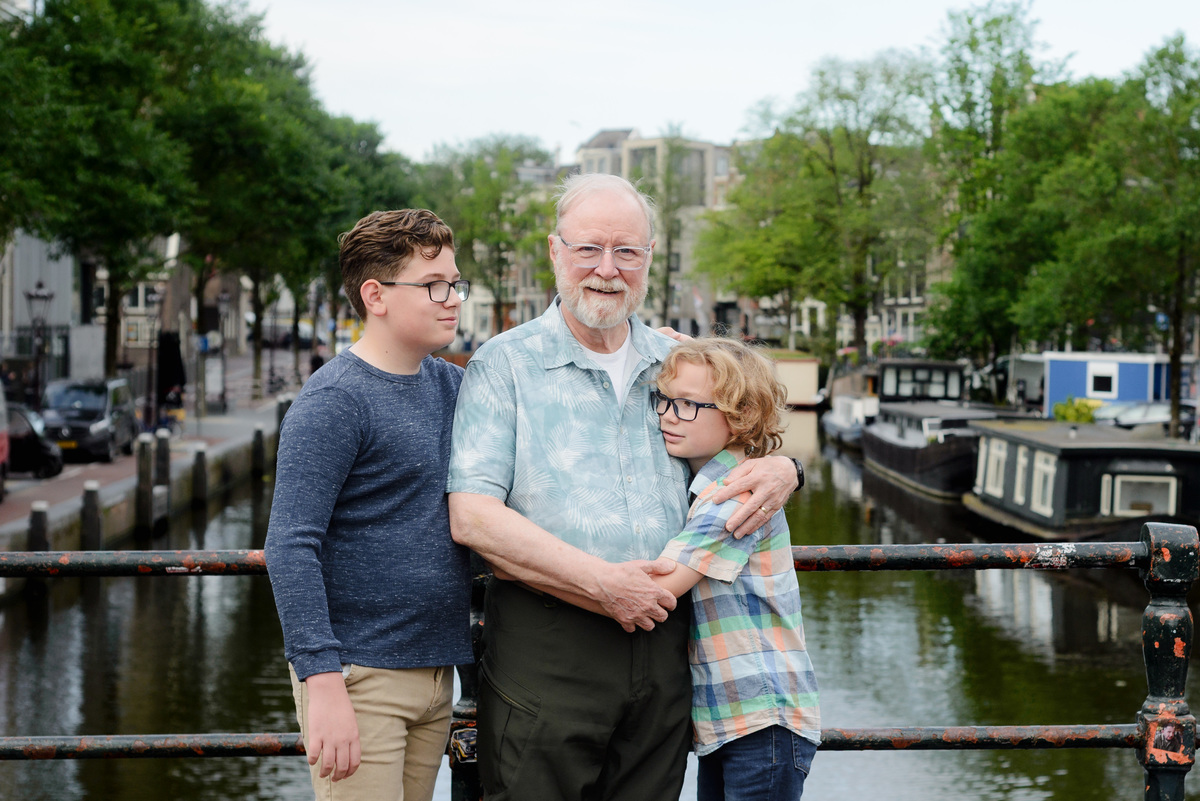 Grandfather and grandkids photographed together beside an Amsterdam canal house