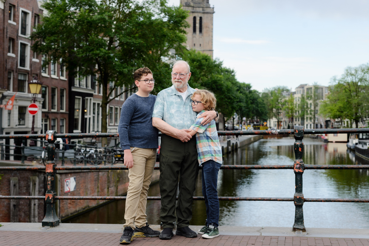 Grandfather and grandkids photographed together beside an Amsterdam canal house