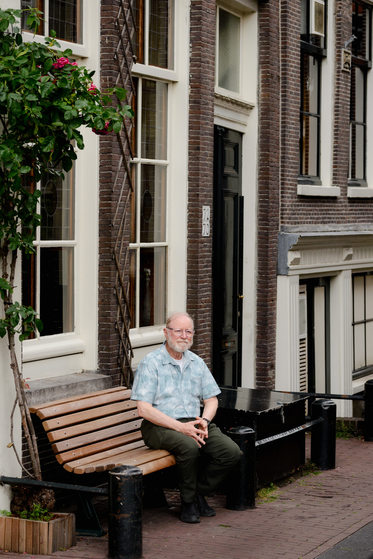 Grandfather sitting on a bench next to a historical canal house in the Jordaan area in Amsterdam 