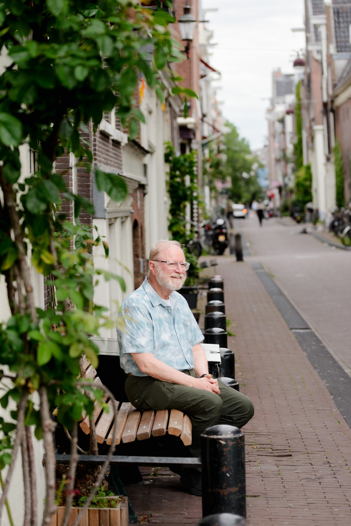 Grandfather sitting on a bench next to a historical canal house in the Jordaan area in Amsterdam 