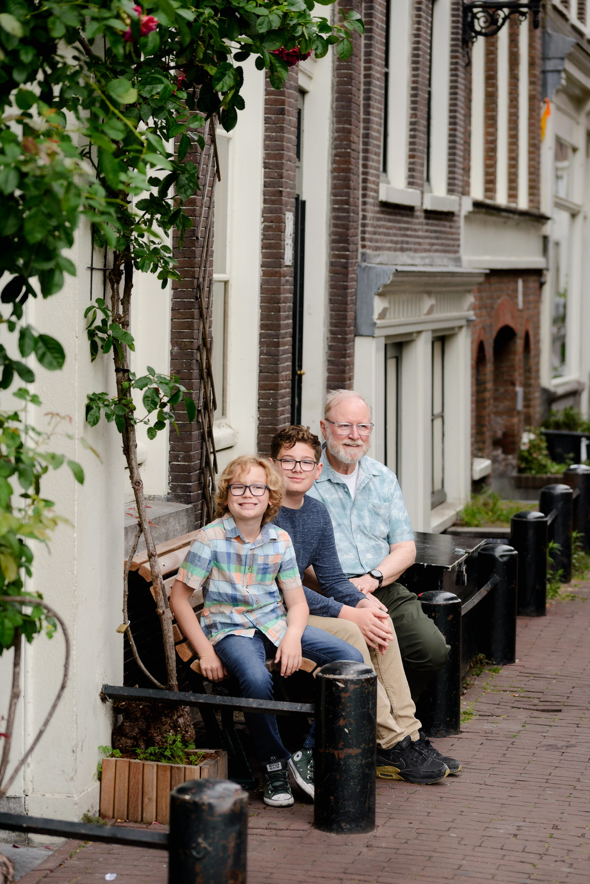 Grandfather and grandkids photographed together beside an Amsterdam canal house