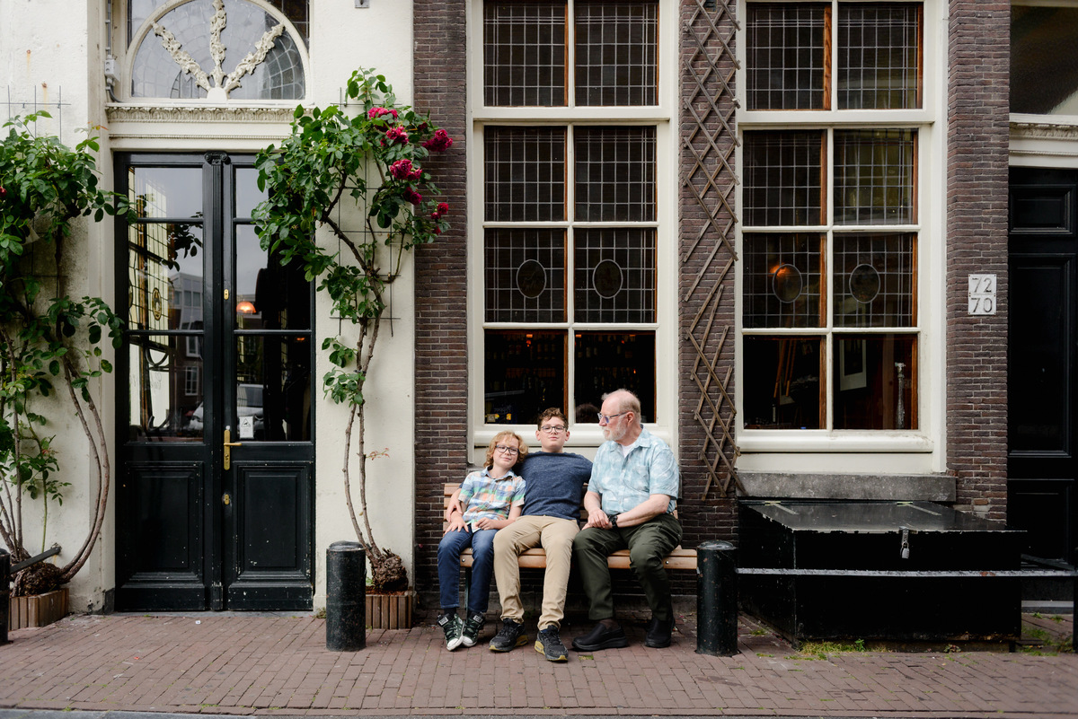 Grandfather and grandkids photographed together beside an Amsterdam canal house