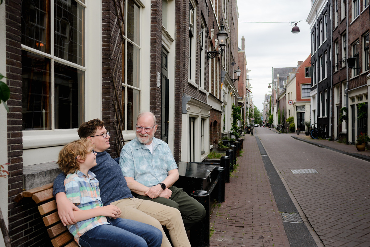 Grandfather and grandkids photographed together beside an Amsterdam canal house