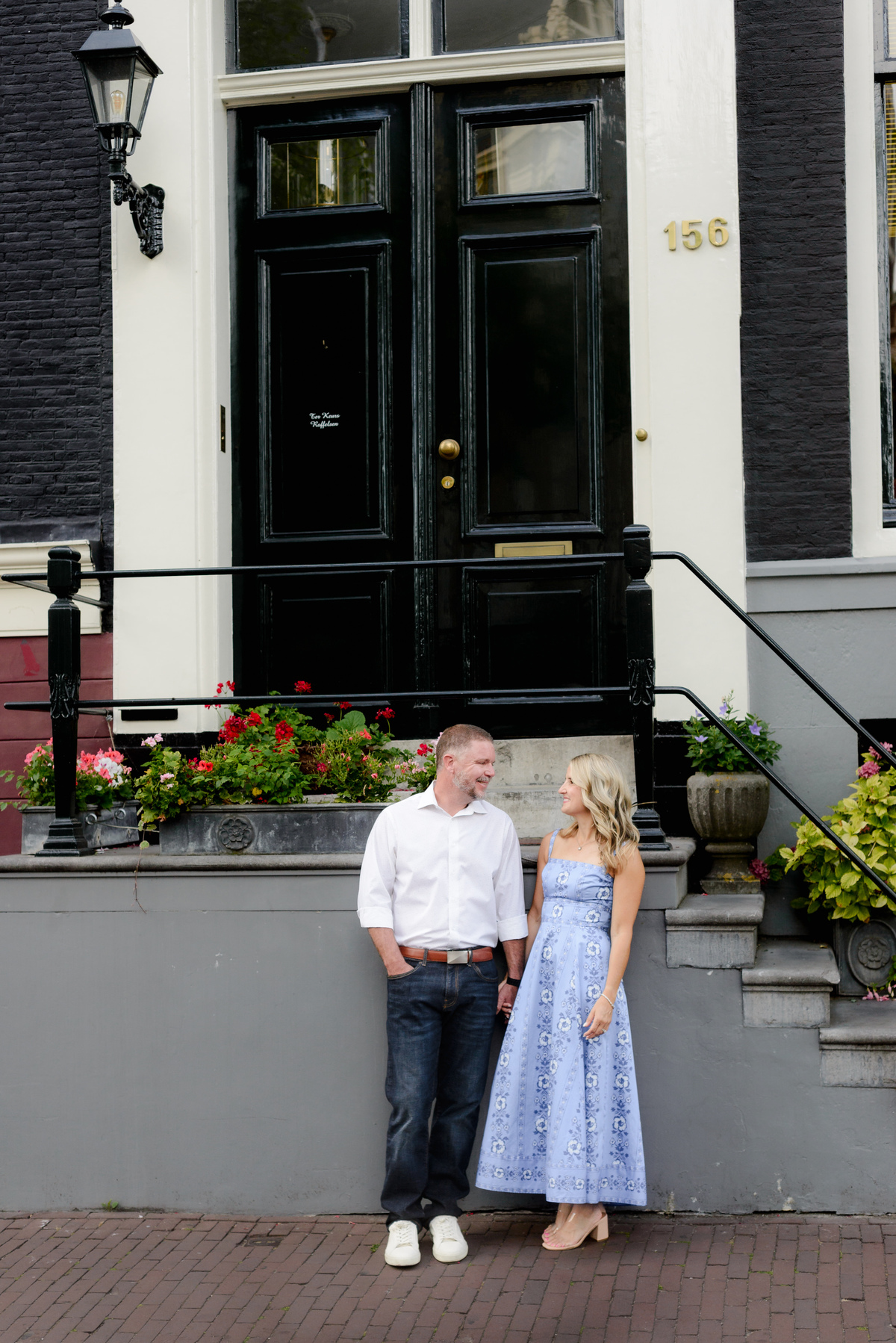 Couple looking at each other, standing next to a canal house in the Jordaan area in Amsterdam during a photoshoot 