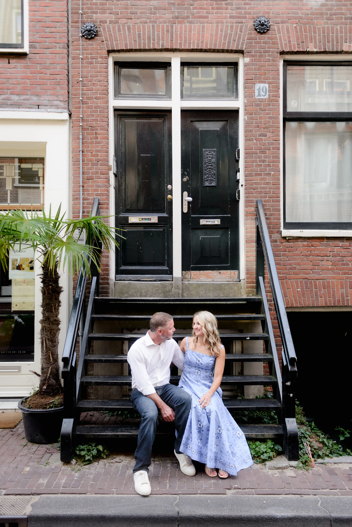 Couple sitting on the steps of a traditional Amsterdam house