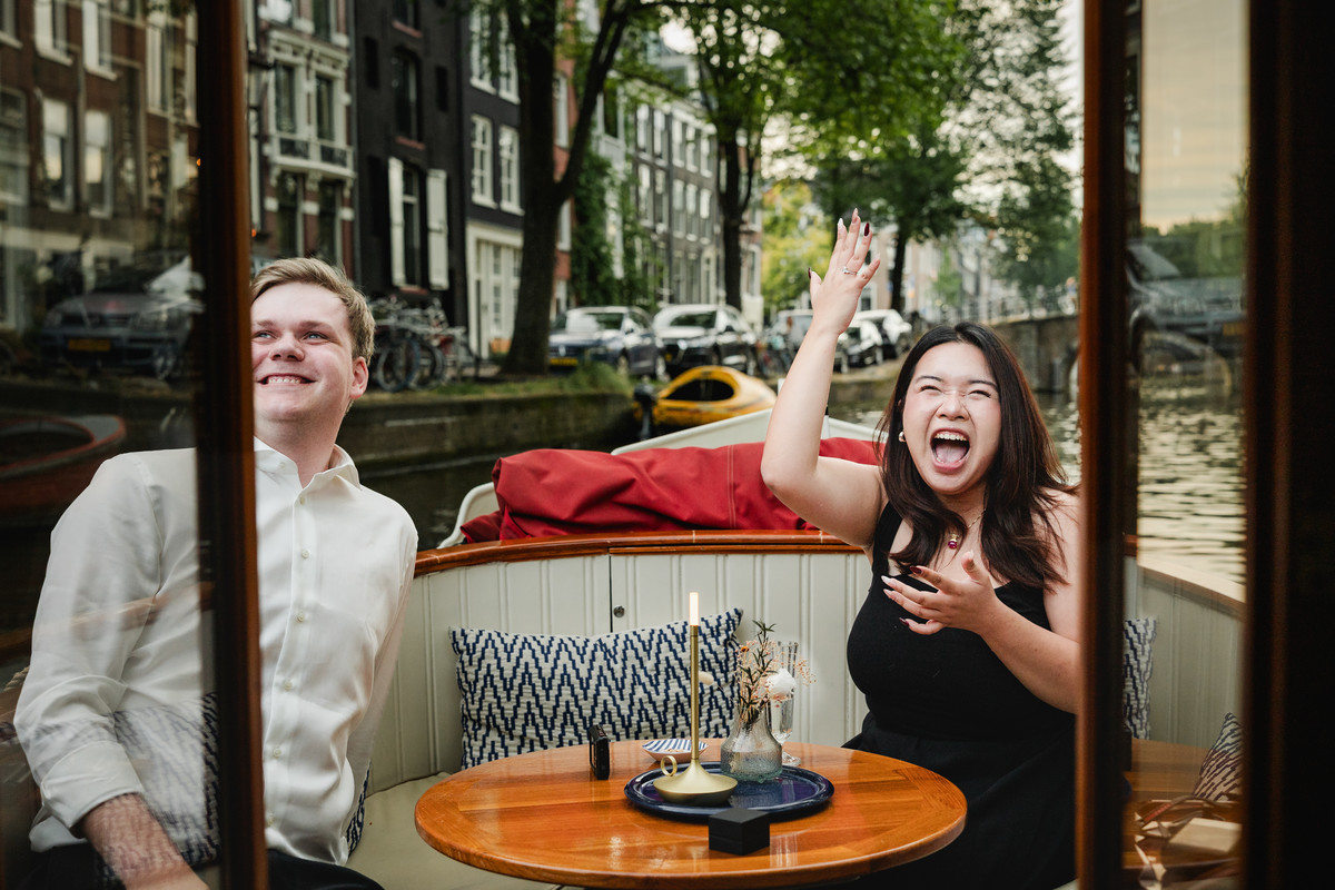 Couple reacting as people beside the canal cheer their proposal