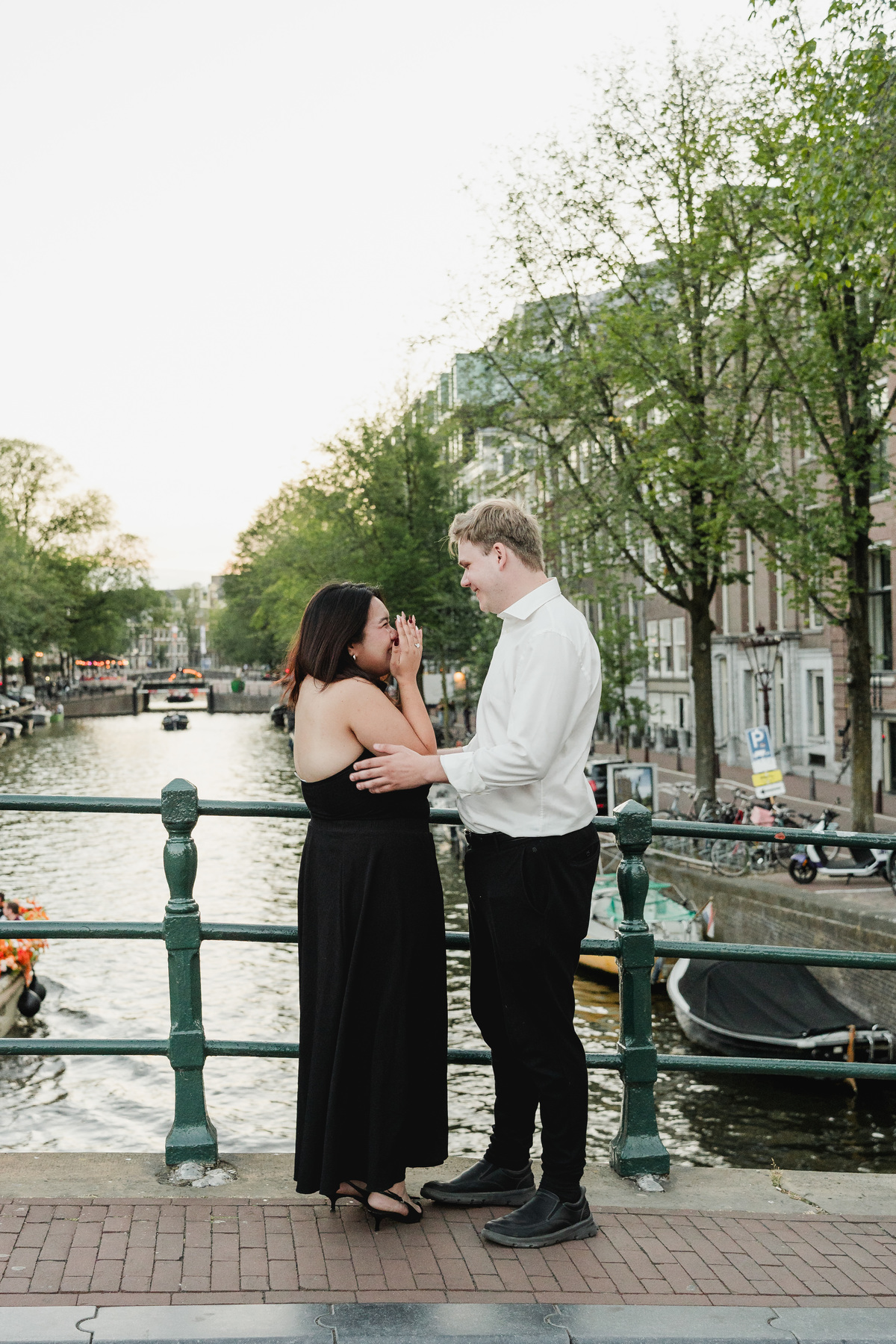 Newly engaged couple photographed beside an Amsterdam bridge