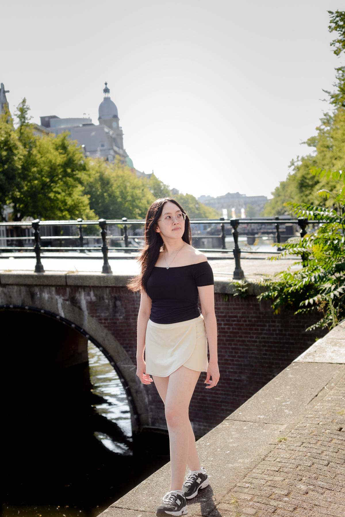 Woman smiling naturally beside a bridge during an Amsterdam travel session
