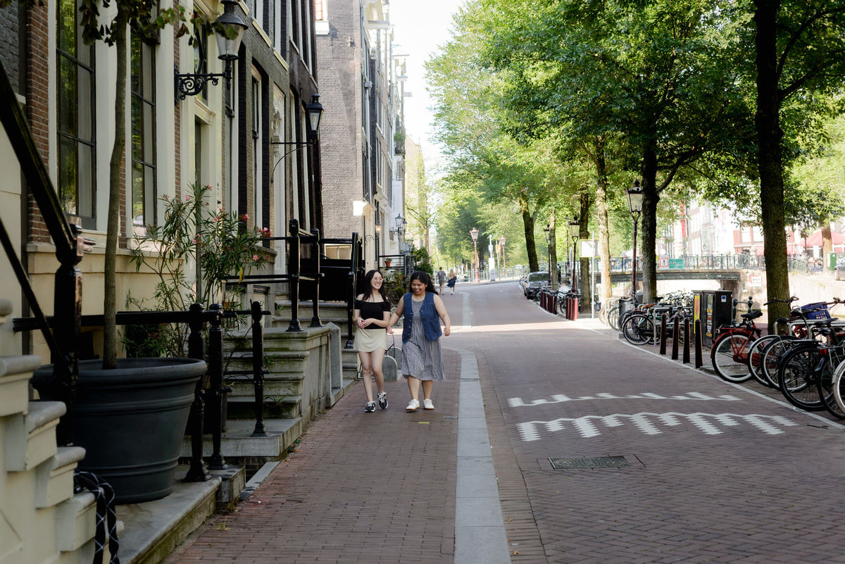 Two friends walking together along a quiet canal street in Amsterdam