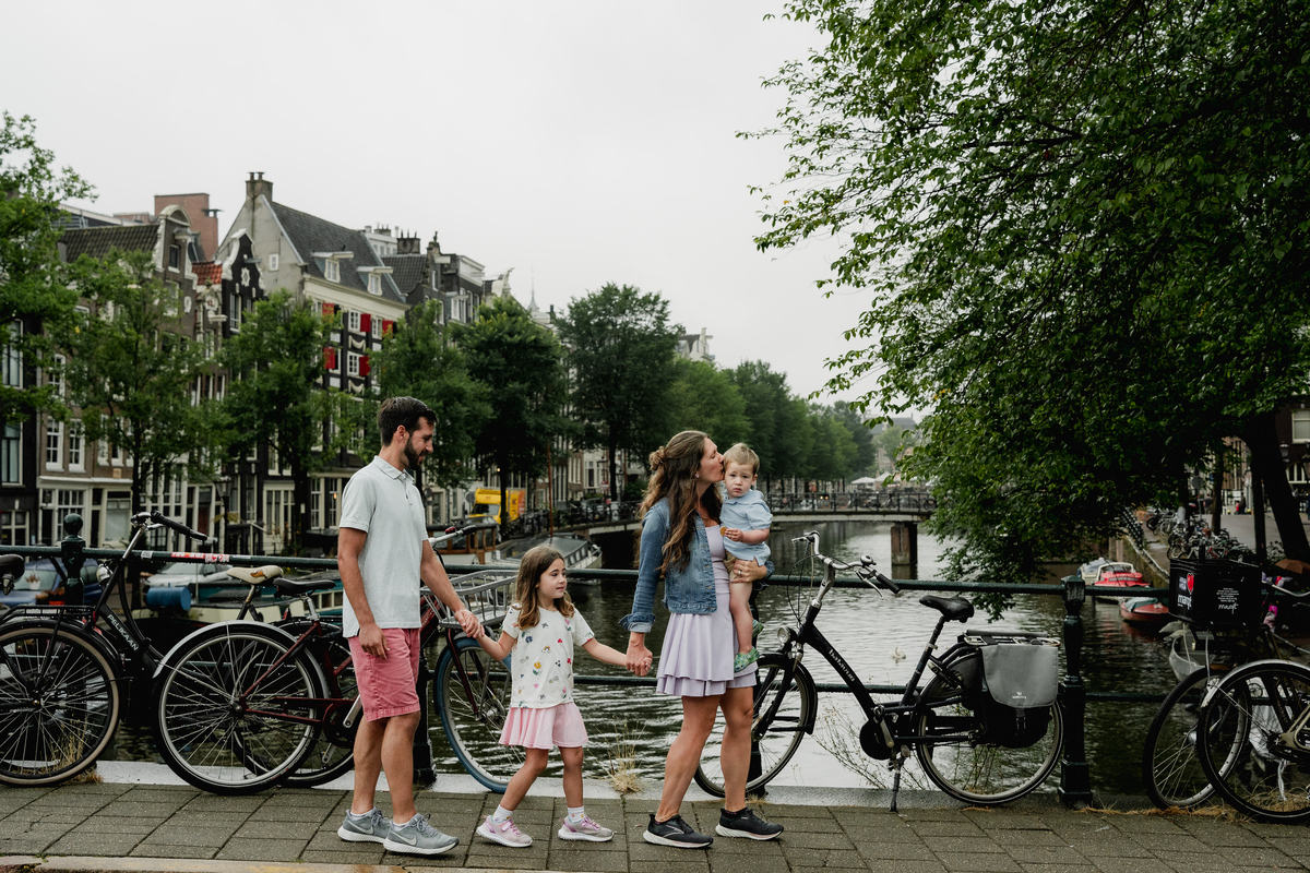 Family walking across an Amsterdam bridge lined with bicycles.