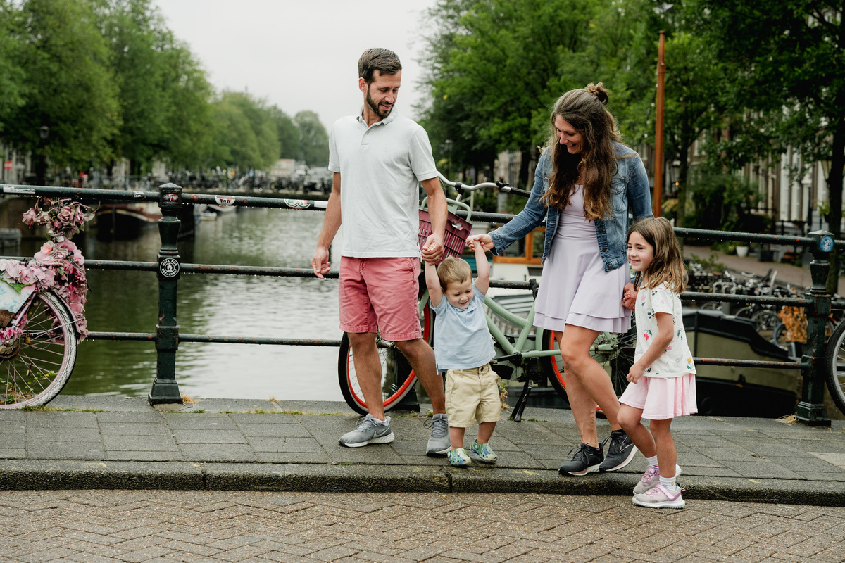Parents looking toward their children while standing together on a canal bridge.