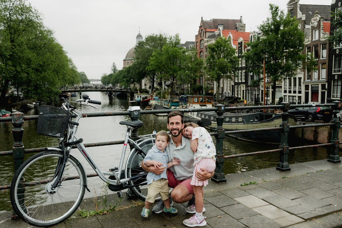 Father crouching beside their children for a family portrait by the canal.