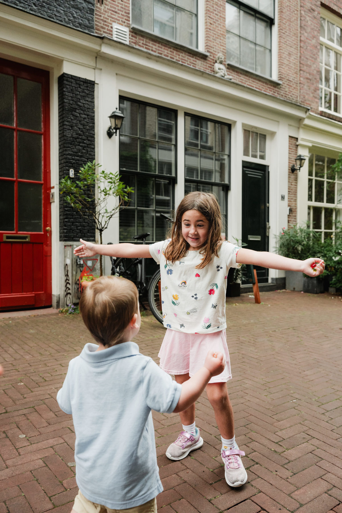 Girl stretching out her arms while playing with her younger brother.