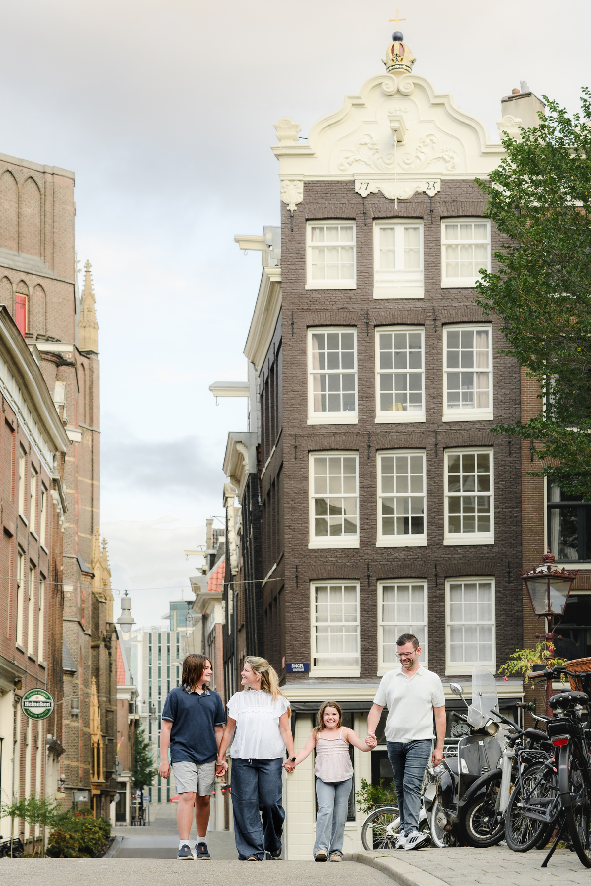 Family walking next to a canal in Amsterdam with historical houses in the background 