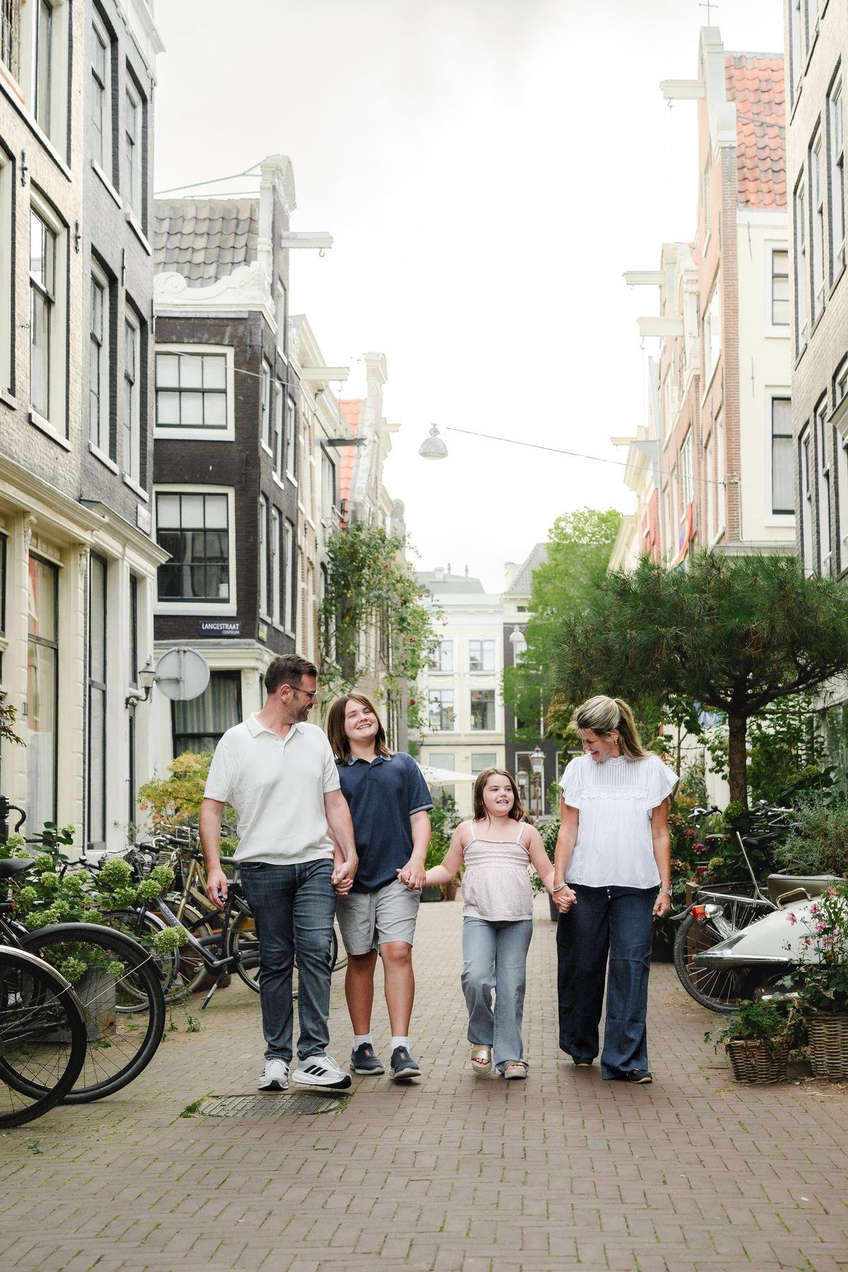 Family walking during their photo session in Amsterdam on a cobblestone street surrounded by historical monumental houses 