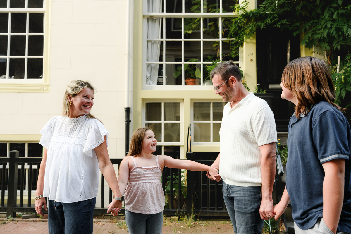 Family walking during their photo session in Amsterdam on a cobblestone street surrounded by historical monumental houses 