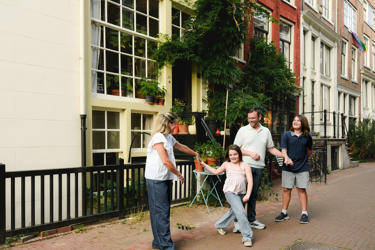 Family walking during their photo session in Amsterdam on a cobblestone street surrounded by historical monumental houses 