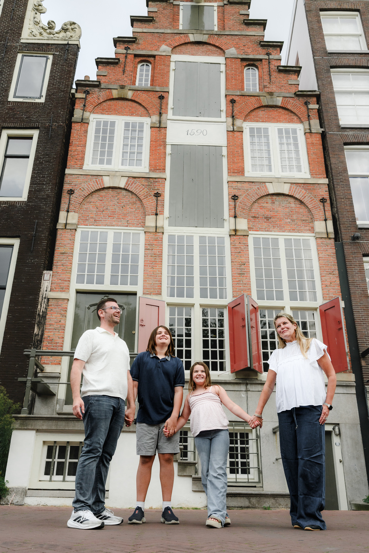 Family is standing in front of one old house in Amsterdam during their photo session. 