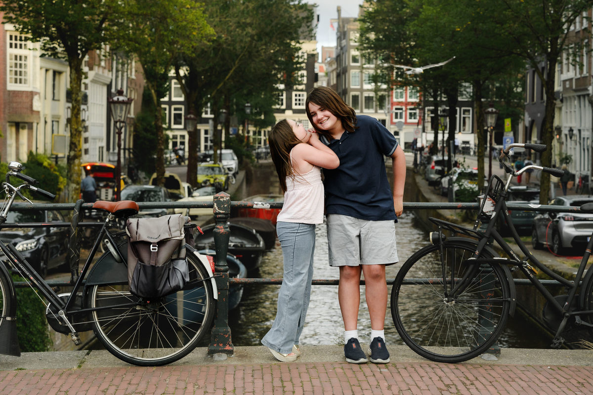 Siblings standing on a bridge with a beautiful canal and historical houses in the background. This was during their family photo session in Amsterdam. 